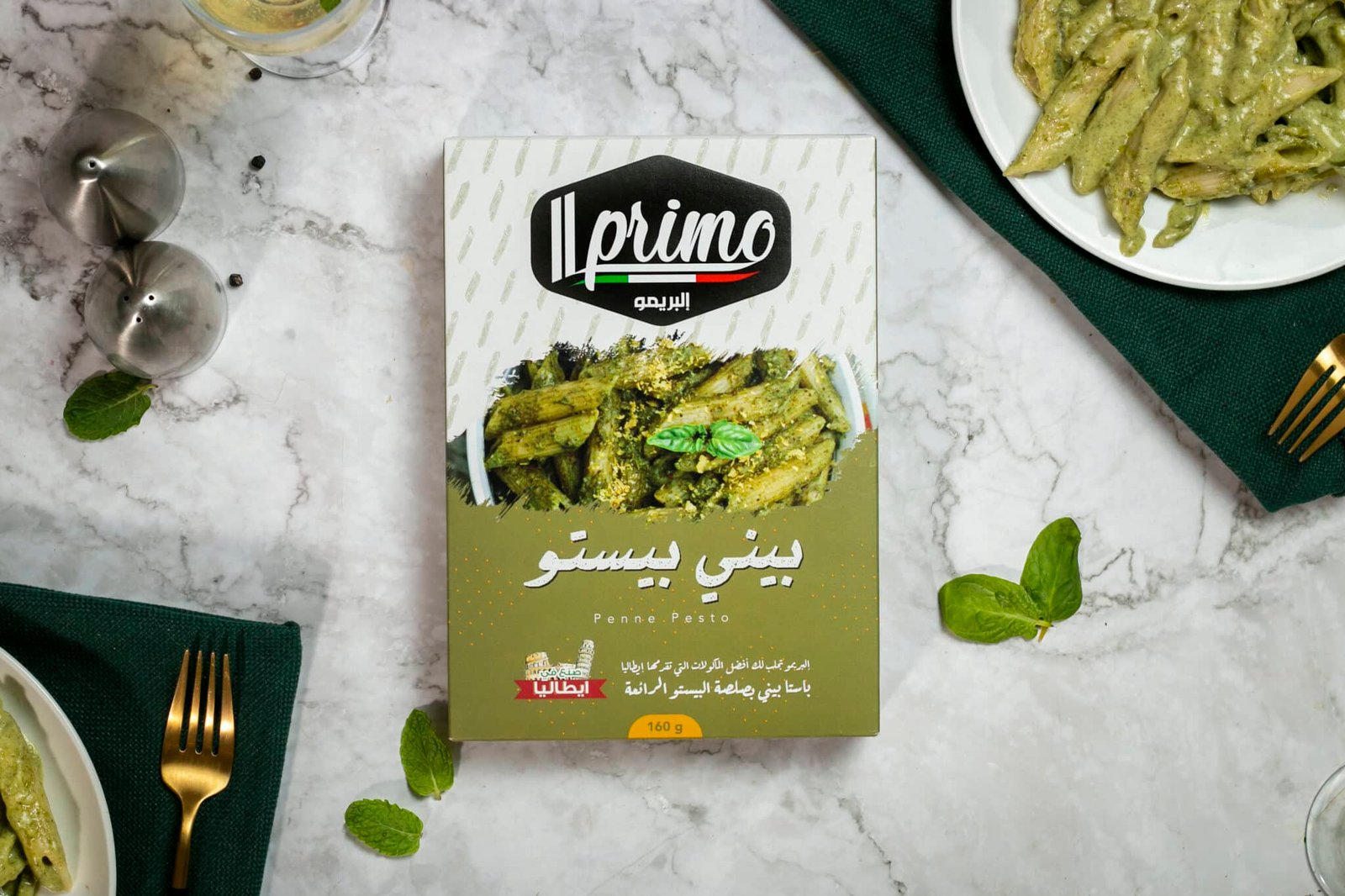 عبوة مكرونة بيني بيستو (Penne Pesto) من ماركة Il Primo بوزن 160 جرام، مع طبقين من المكرونة المطهية بصوص البيستو الأخضر.